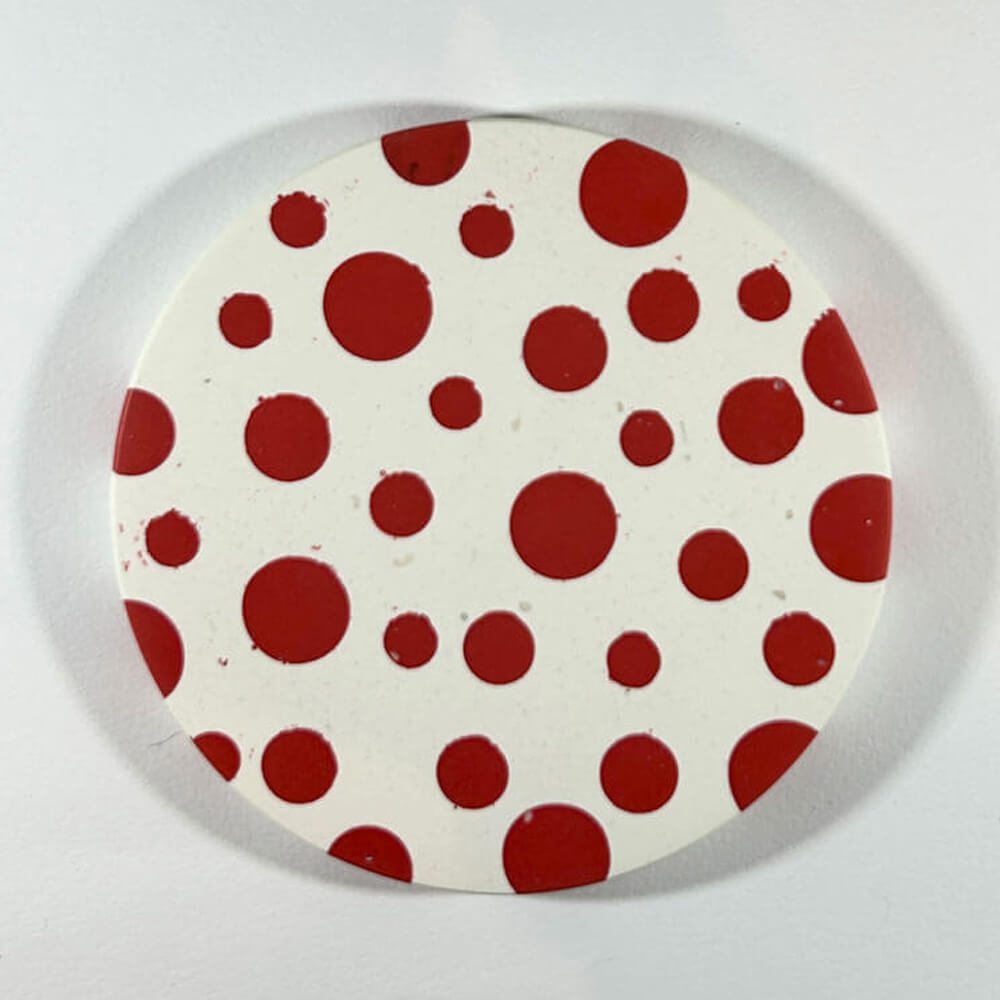 Round coaster with red polka dots on a white background