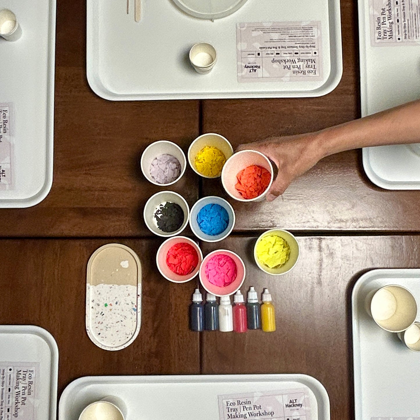 Colourful terrazzo in small bowls on a wooden table with a hand reaching for one of the bowls.