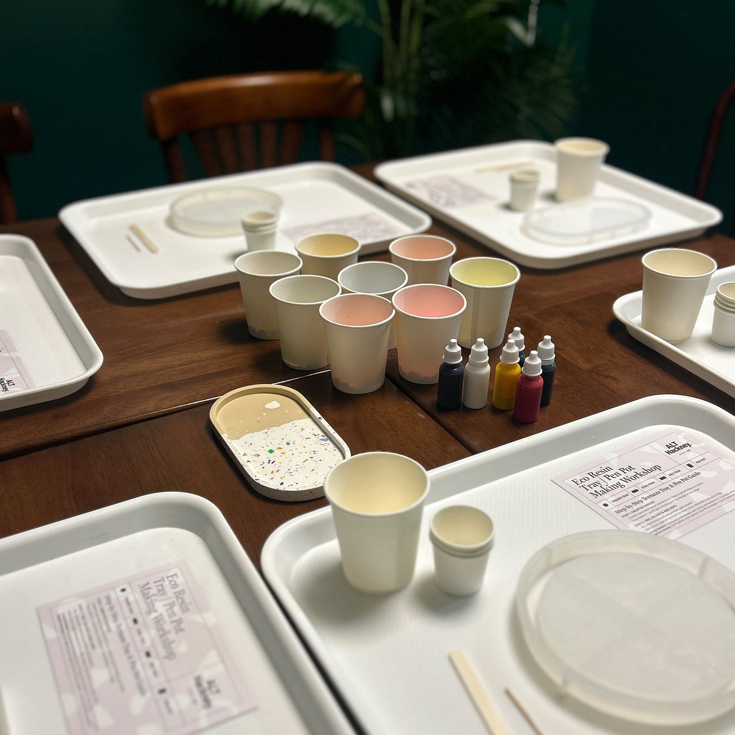 Set of paper cups with pigment bottles on a wooden table