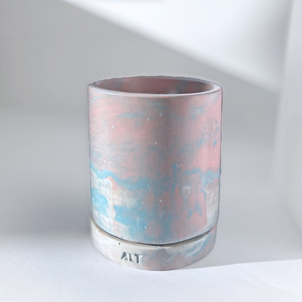 Jesmonite planter with marbled design with a drainage hole and a water tray on a light surface