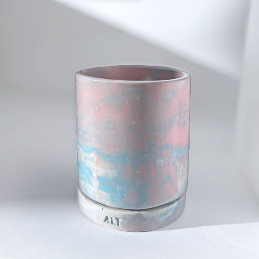 Jesmonite planter with marbled design with a drainage hole and a water tray on a light surface