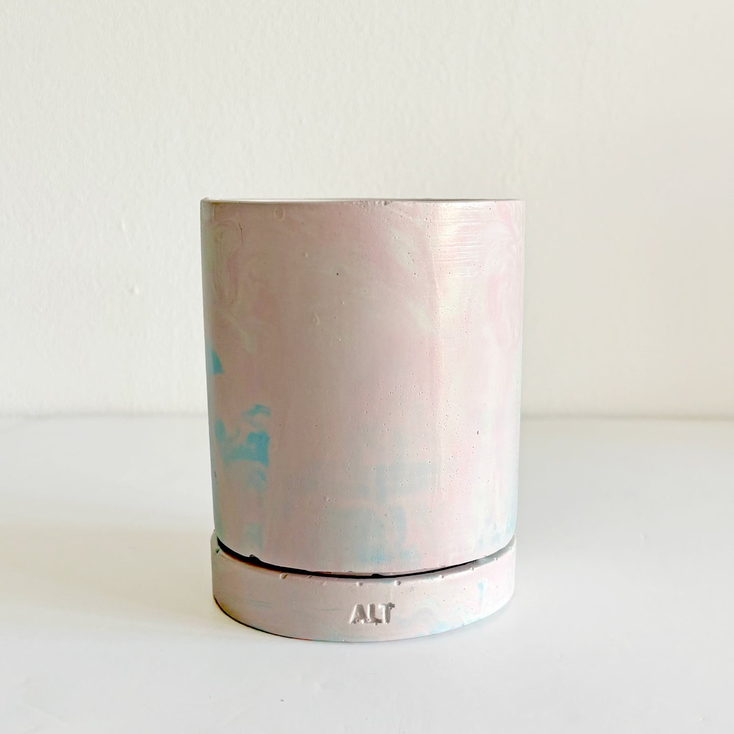 Jesmonite planter with marbled design with a drainage hole and a water tray on a light surface