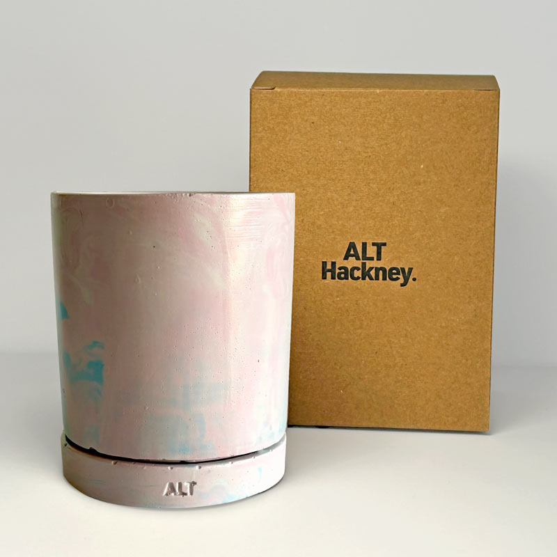 Jesmonite planter with marbled design with a drainage hole and a water tray with 'ALT' branding next to a brown box also featuring 'ALT Hackney'.