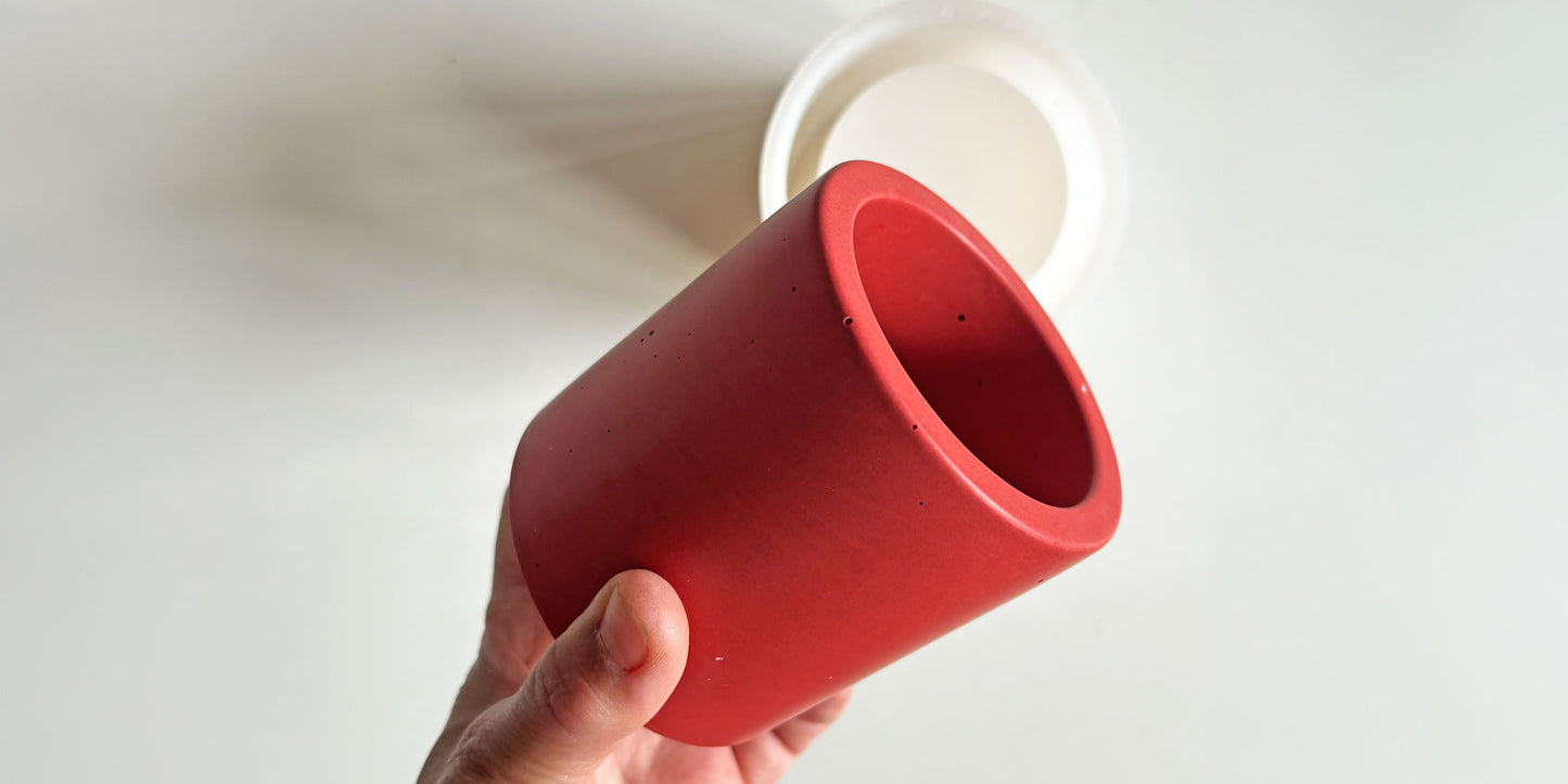 Red terrazzo Pen Pot held by a hand with a clear silicone mould against a white background
