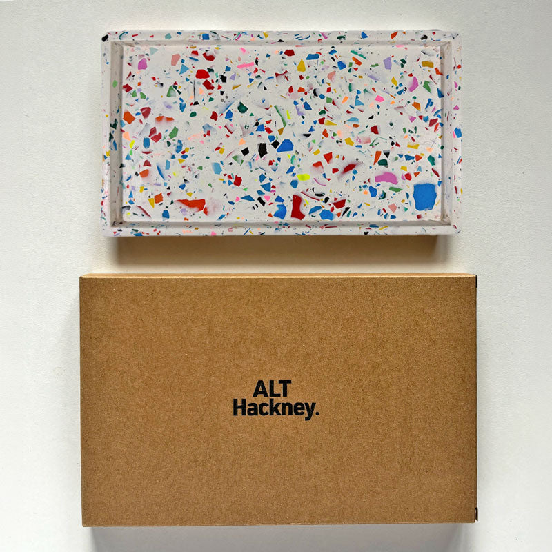 Rainbow terrazzo rectangular tray with a brown eco packaging box with 'ALT Hackney' embossed on it, on a light gray background