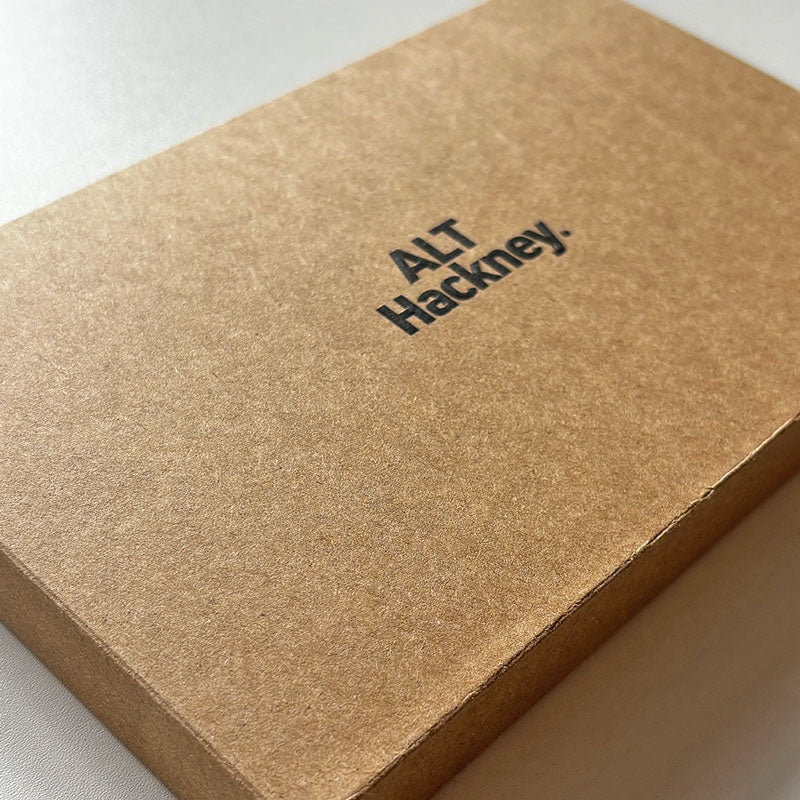 Brown eco packaging box with 'ALT Hackney' embossed on it, on a light gray background
