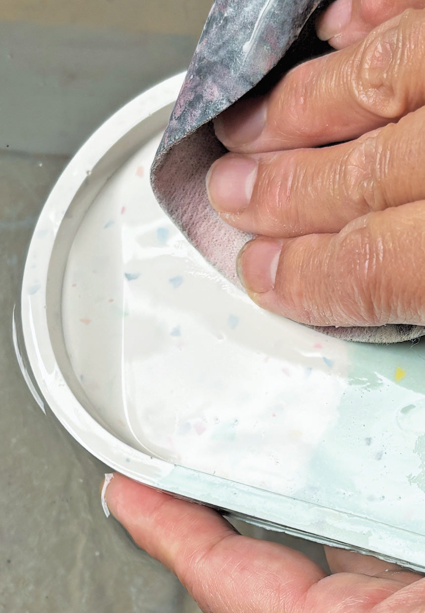 Hand sanding the surface of an eco resin terrazzo oval tray.