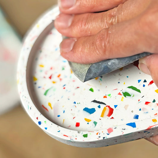 Hand sanding the surface of an eco resin terrazzo oval tray.