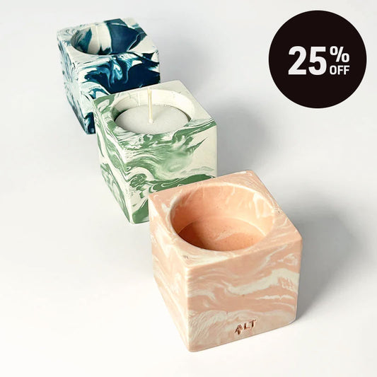 Three square marble candle holders in peach, green, and blue swirl patterns, arranged diagonally on a white background with a black '25% OFF' promotional badge in the top right.