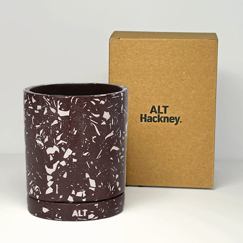 A brown plant pot with a white terrazzo speckled pattern, shown next to its brown cardboard packaging box printed with the brand name 'ALT Hackney'.