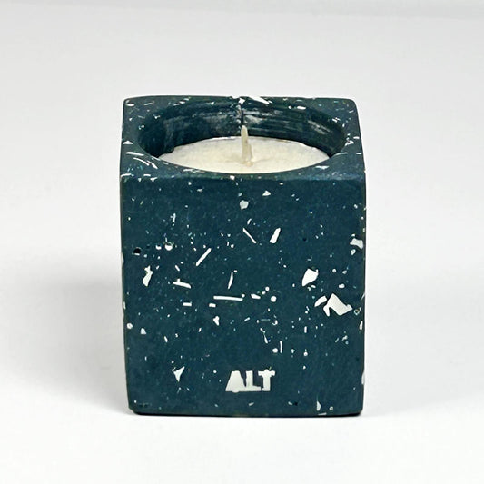 A rectangular navy candle holder with white terrazzo, containing a white tea light candle. The word 'ALT' is printed in white near the bottom front.