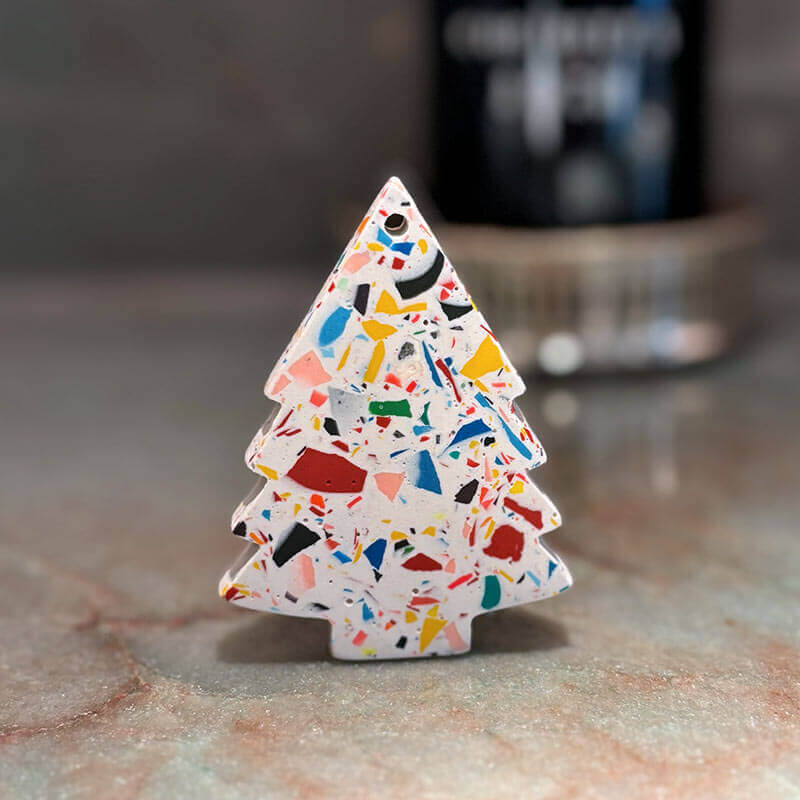 Colorful terrazzo-patterned Christmas tree decoration on a marble surface.