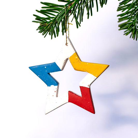 Colorful star-shaped Christmas ornament hanging on a tree branch with shadow 
