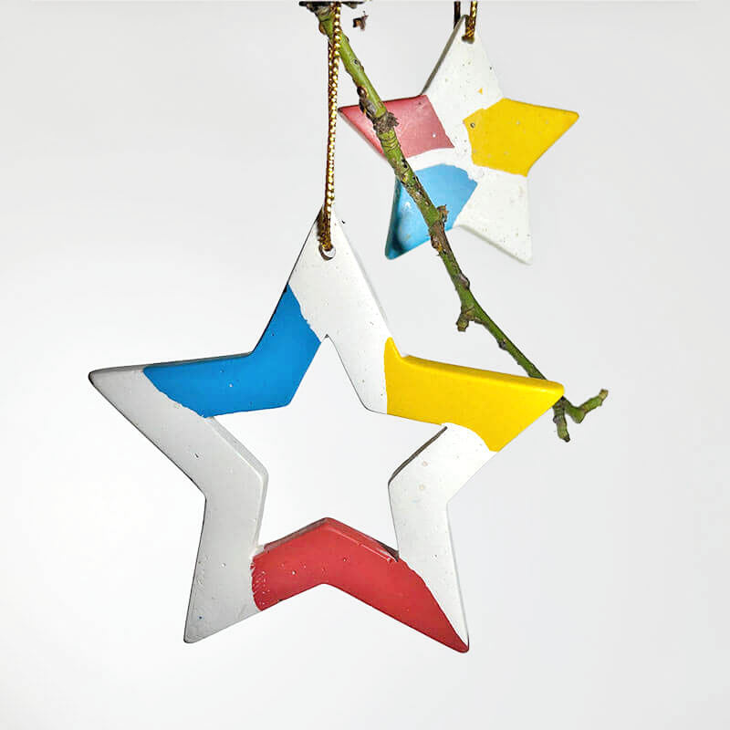 Colorful star-shaped Christmas ornaments hanging on a branch against a white background