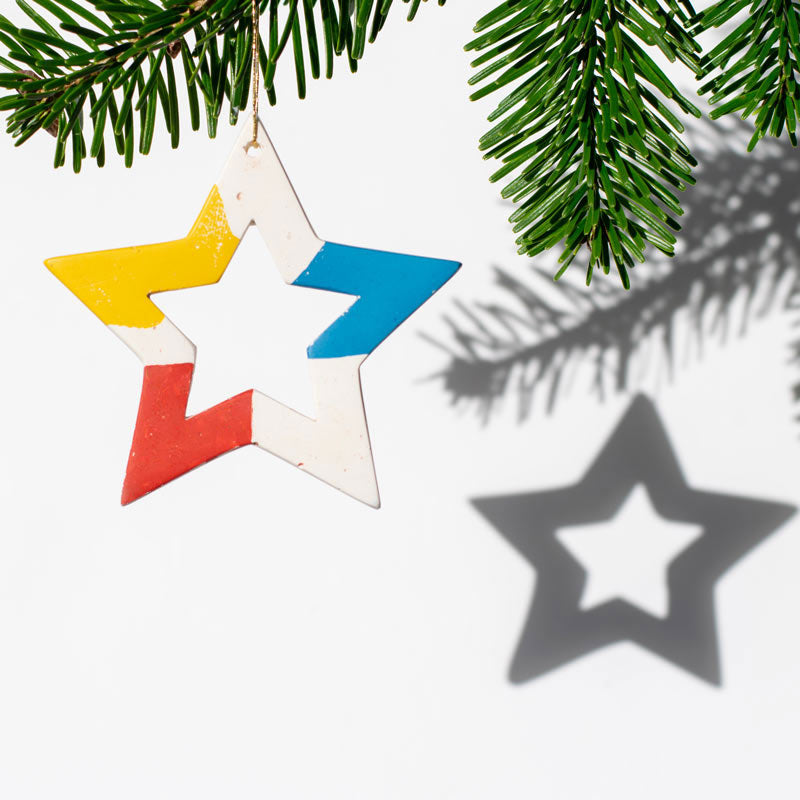 Colorful star-shaped ornament hanging on a branch with a clear background