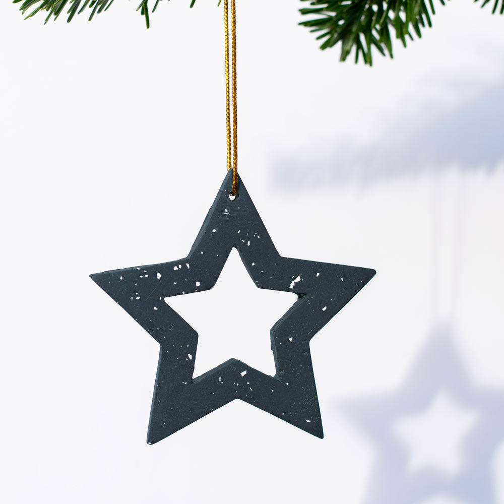 Navy with white terrazzo star hanging from a tree branch on a white background