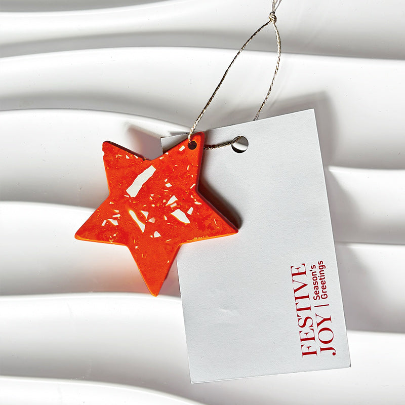 Orange terrazzo star-shaped ornament on a white card with Festive Joy red text on a white background