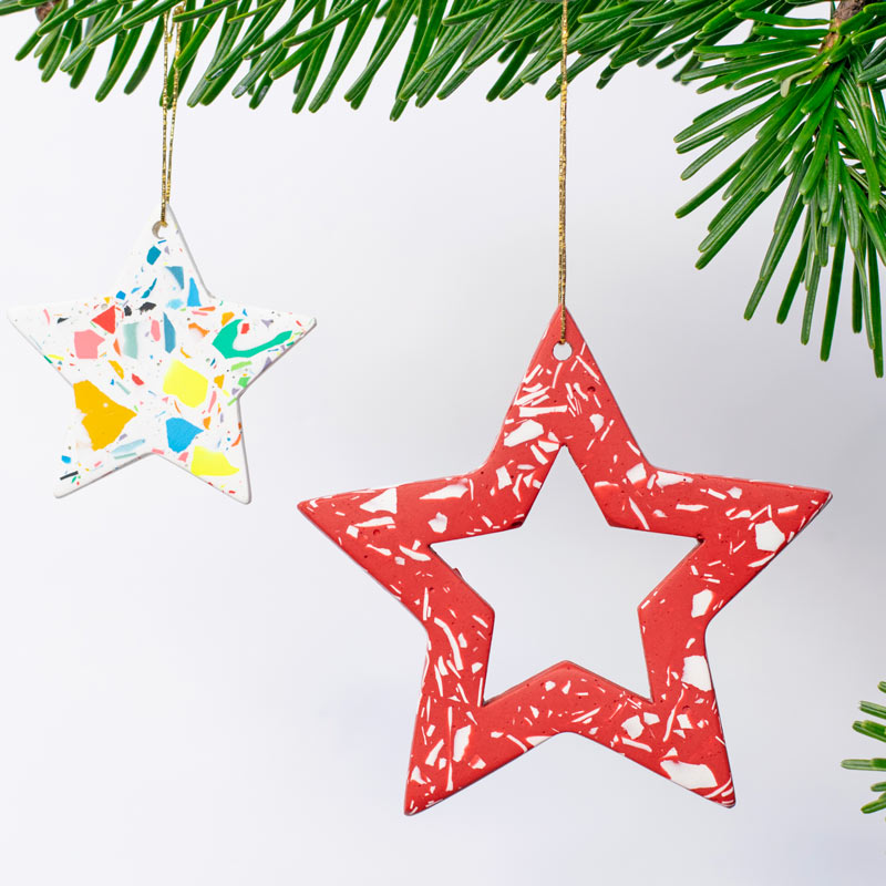Red star-shaped ornament with white with rainbow confetti terrazzo hanging on a branch