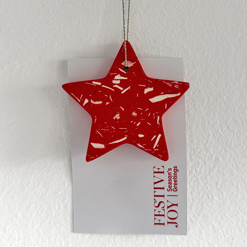Red star-shaped terrazzo ornament on a white card with 'Festive Joy' text against a white background