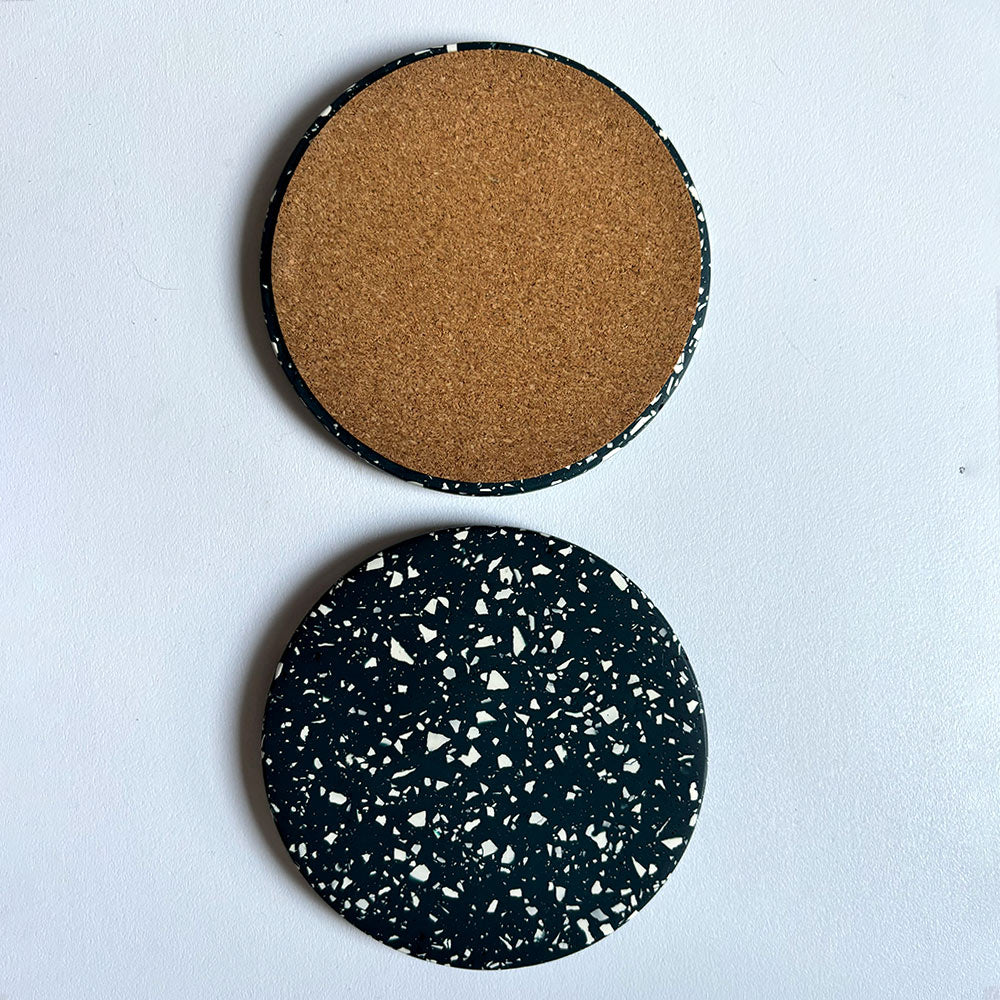 Two navy terrazzo round coasters on a light gray background