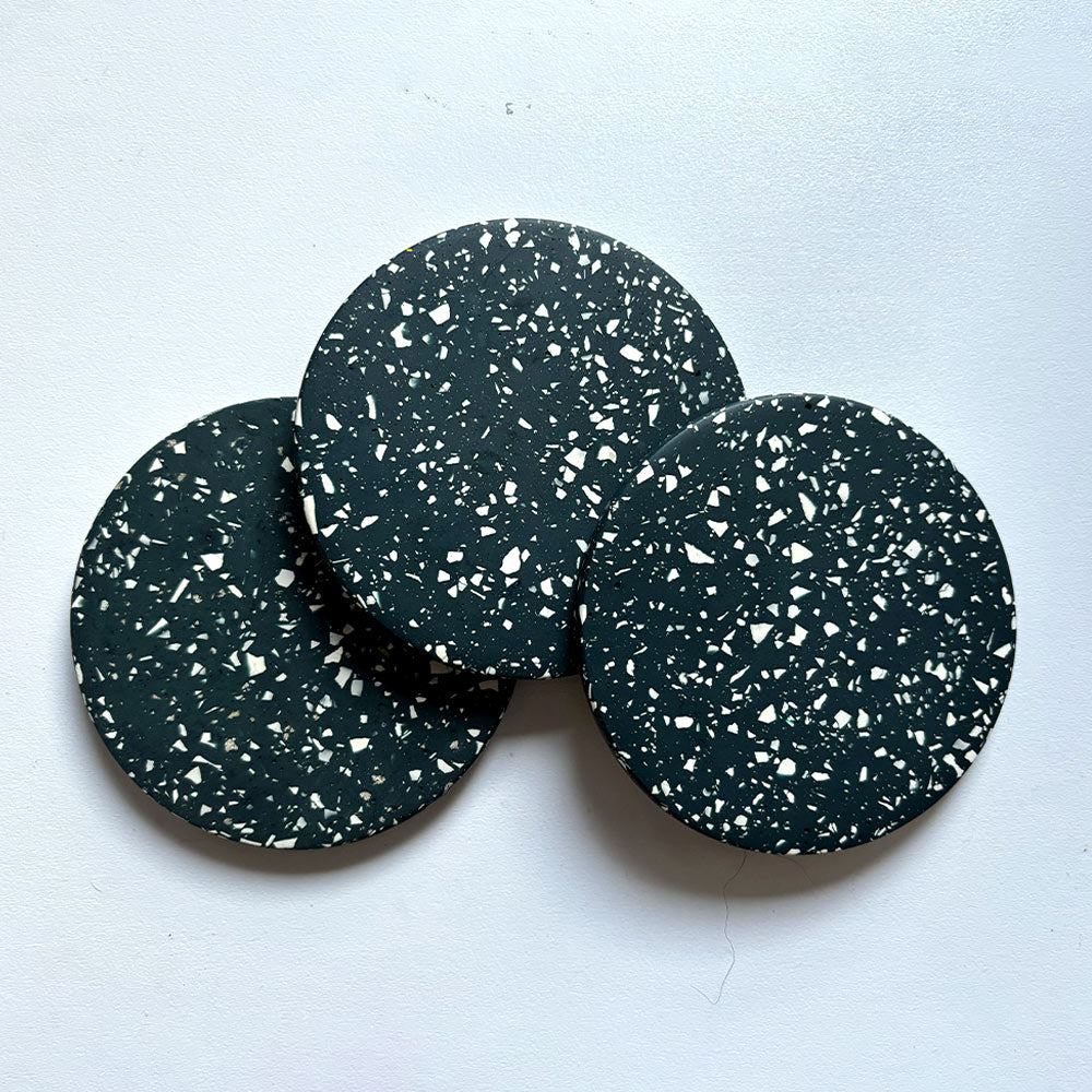 Three navy terrazzo round coasters on a light gray background