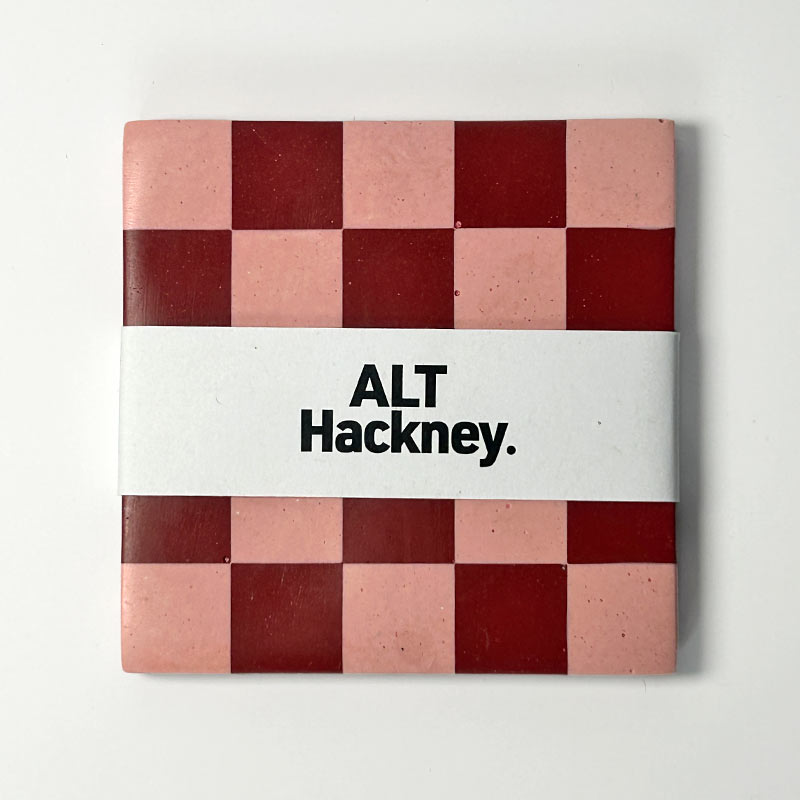 Dard red and pink checkered coaster with 'ALT Hackney.' belly band on a white background