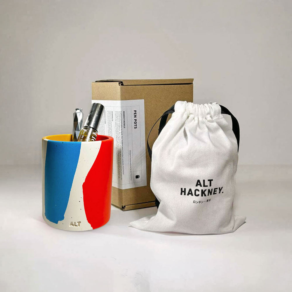 Colourful pen holder with a white drawstring bag and box on a light gray background