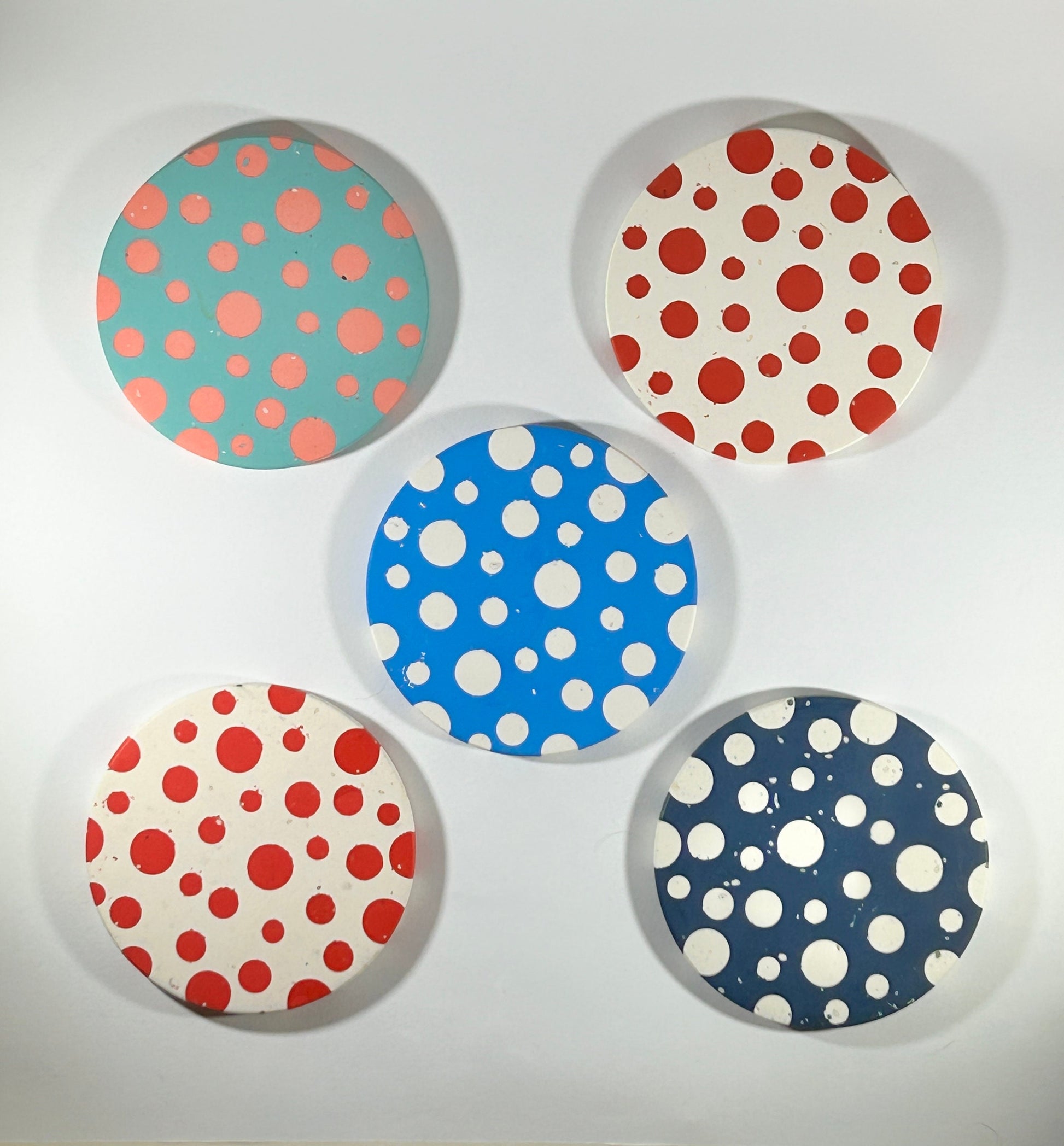 Five circular coasters with polka dot patterns on a white background