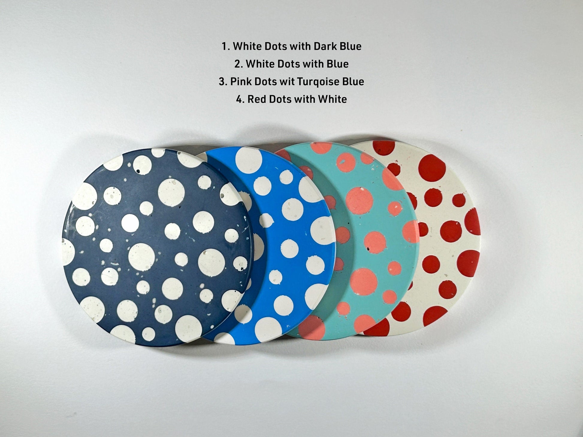 Four polka dot coasters in different colour combinations on a white background.