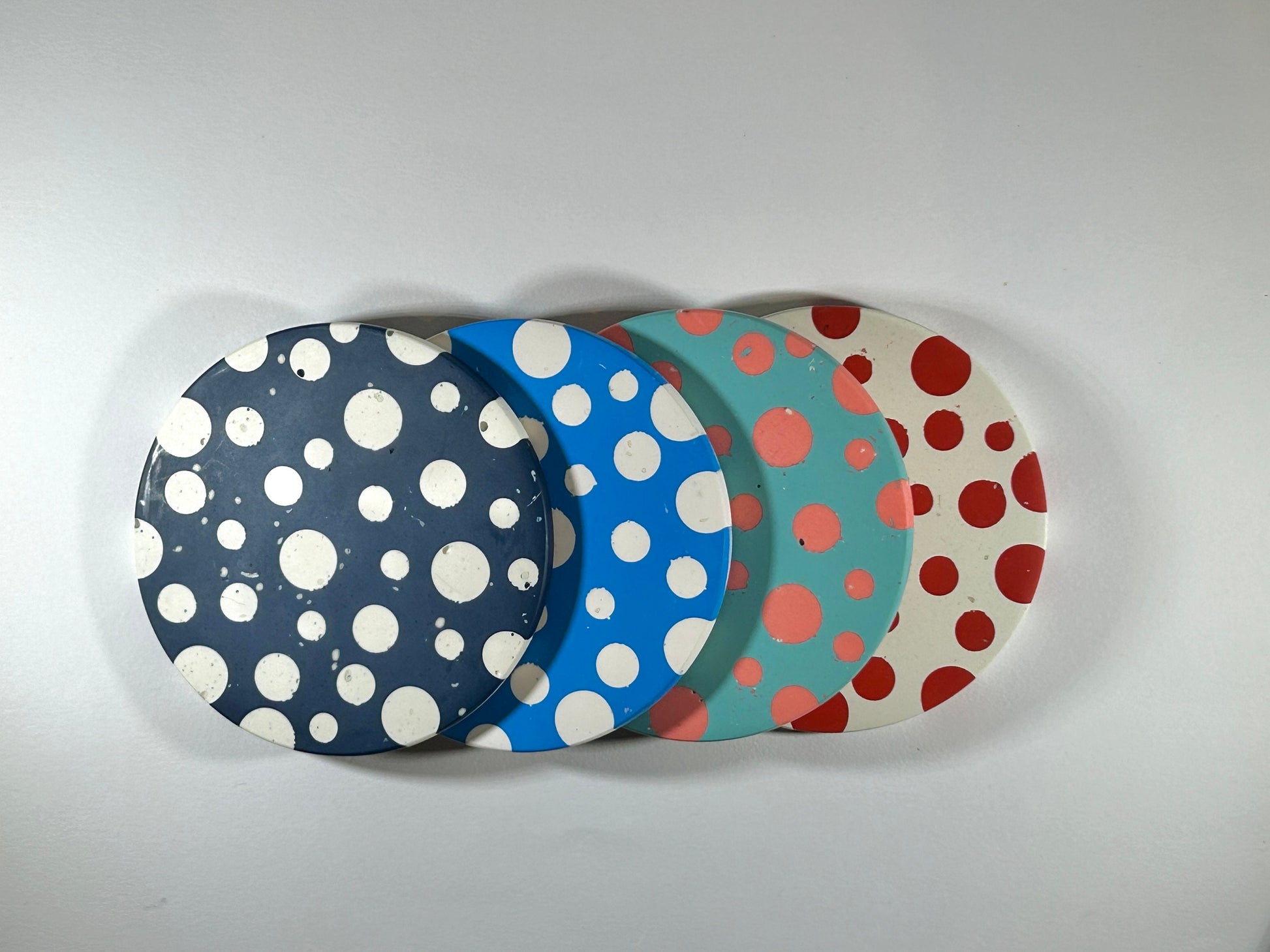 Four polka dot coasters in different colours on a white background