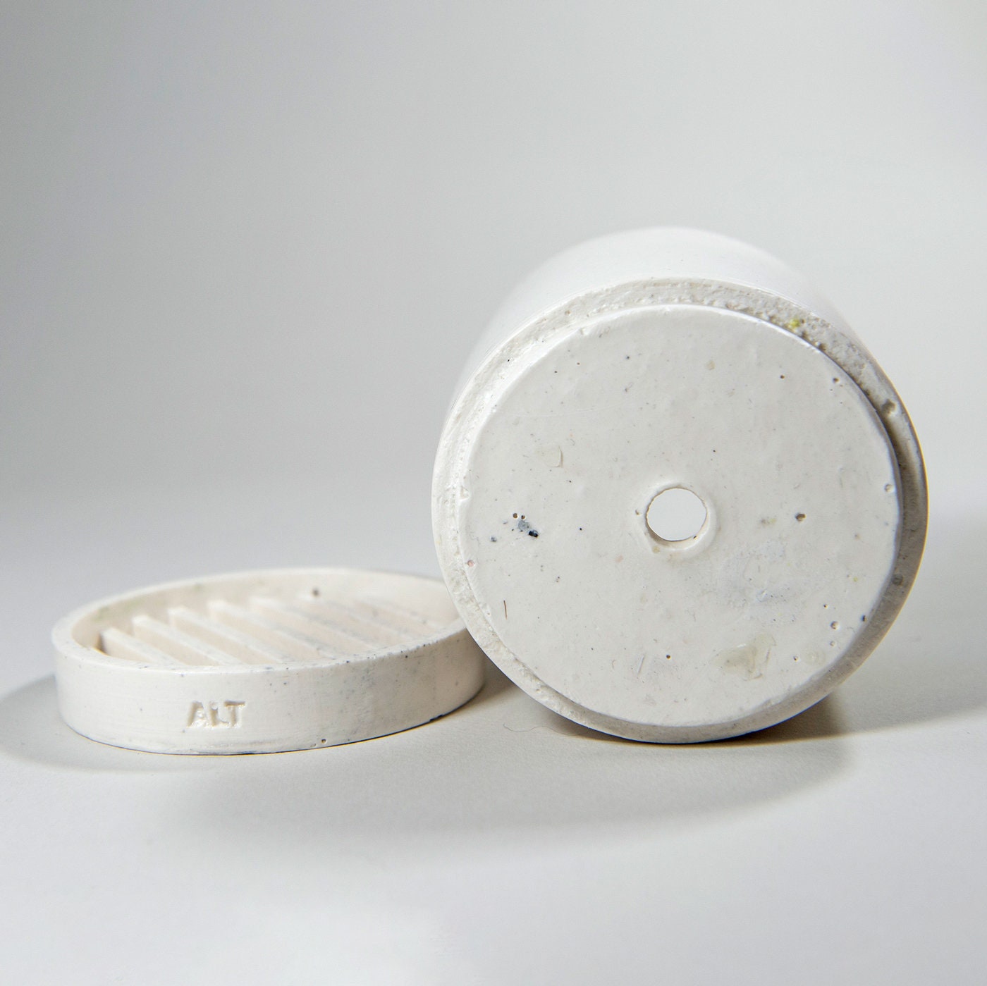 White eco friendly Jesmonite container with a drainage hole with a separate water tray on a light gray background