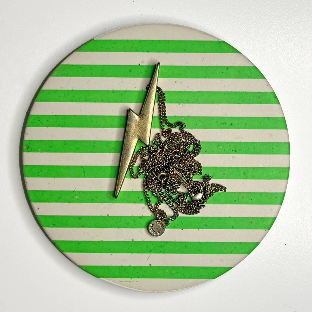Neon green and white stripes coaster featuring a gold lightning bolt and chain necklace