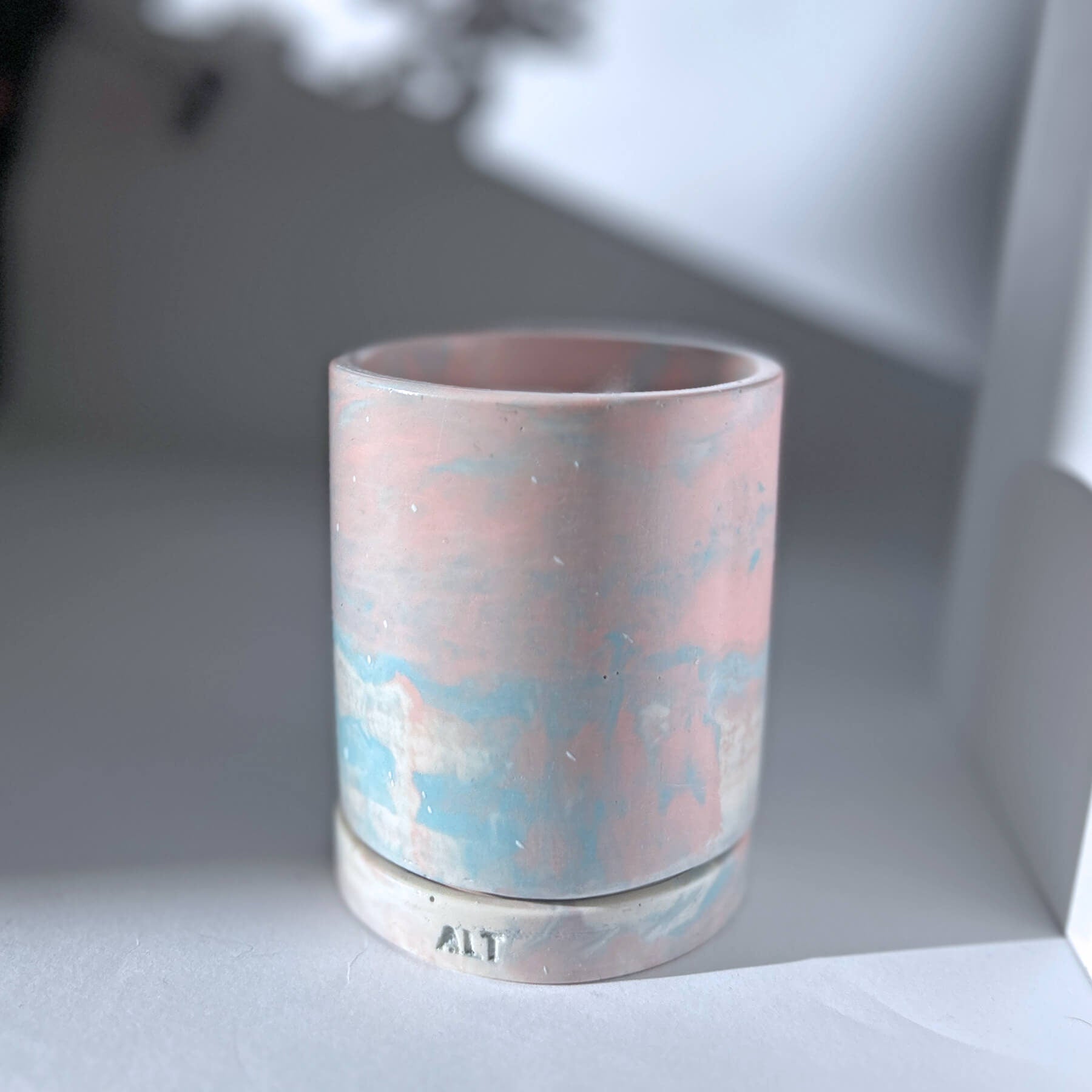 Jesmonite planter with marbled design with a drainage hole and a water tray on a light surface