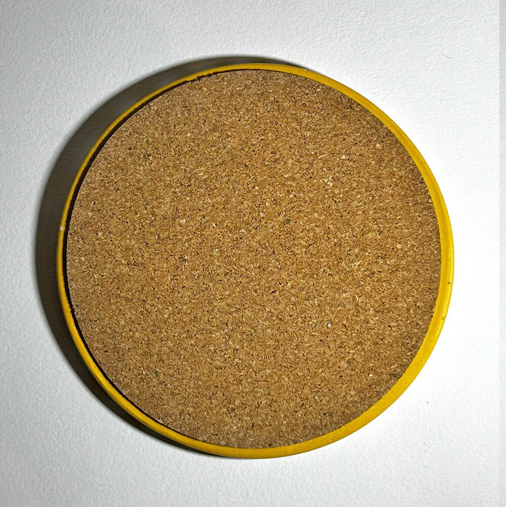 Round cork coaster with yellow rim on a white background