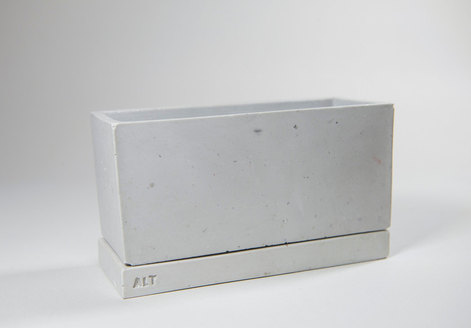 Rectangular grey planter with drainage holes and a water tray box with 'ALT' branding on a white background