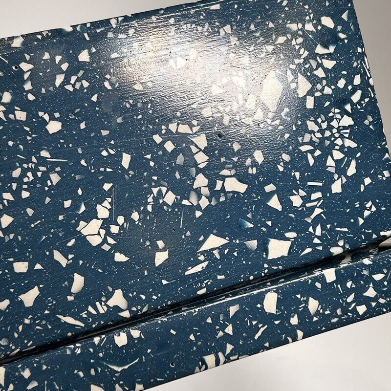 Close up of a navy rectangular terrazzo planter with drainage holes and a water tray on a white background
