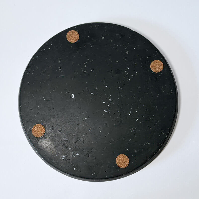 Black speckled decorative tray with corks on a white background