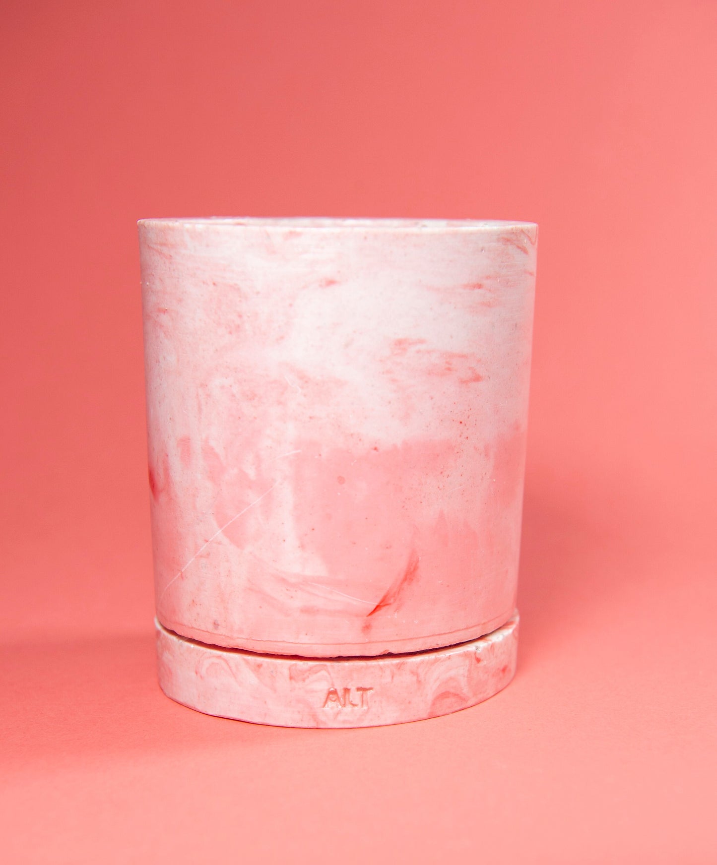 Pink marbled cylindrical plant pot with a drainage and a water tray on a pink background