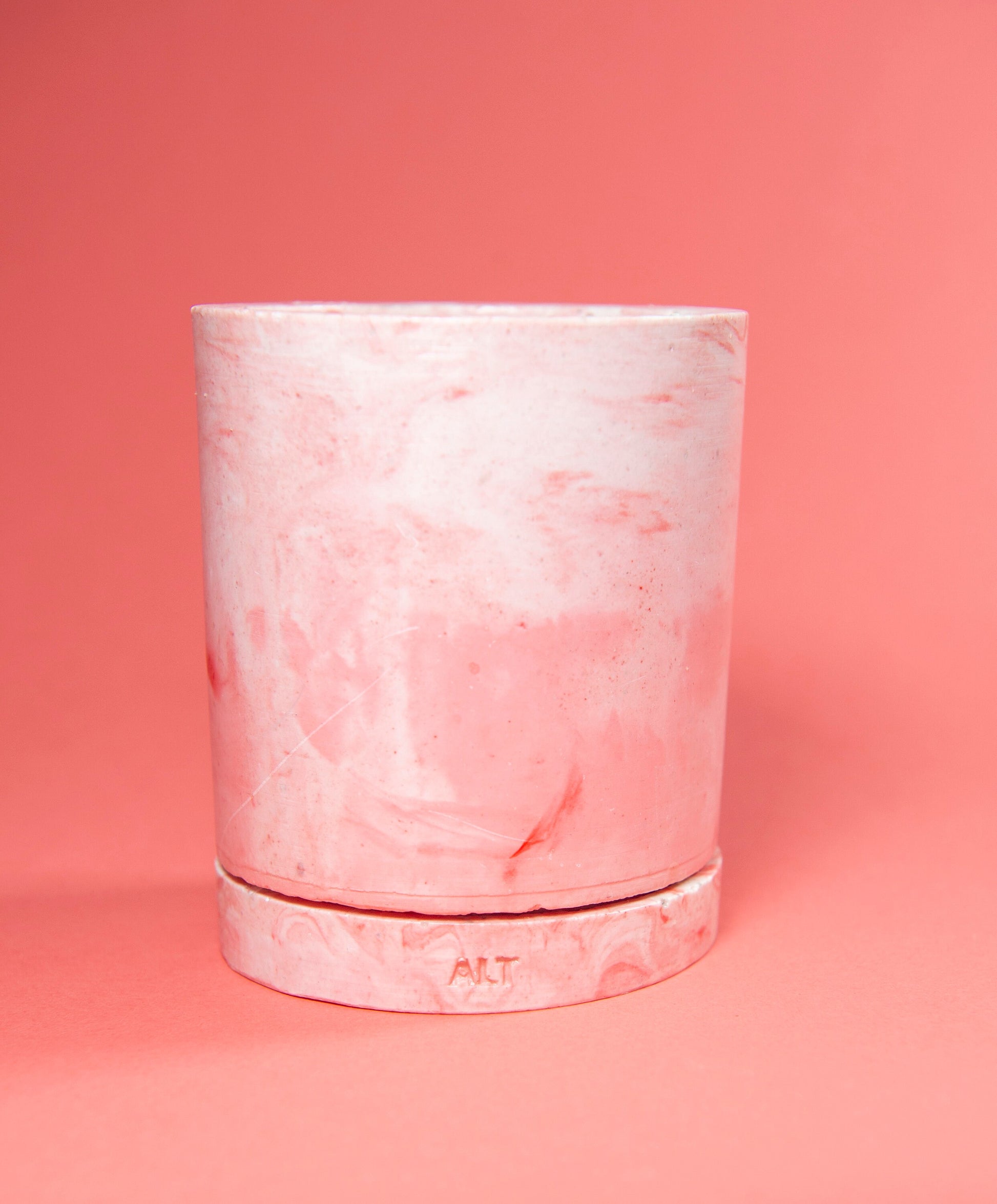Pink marbled cylindrical plant pot with a drainage and a water tray on a pink background