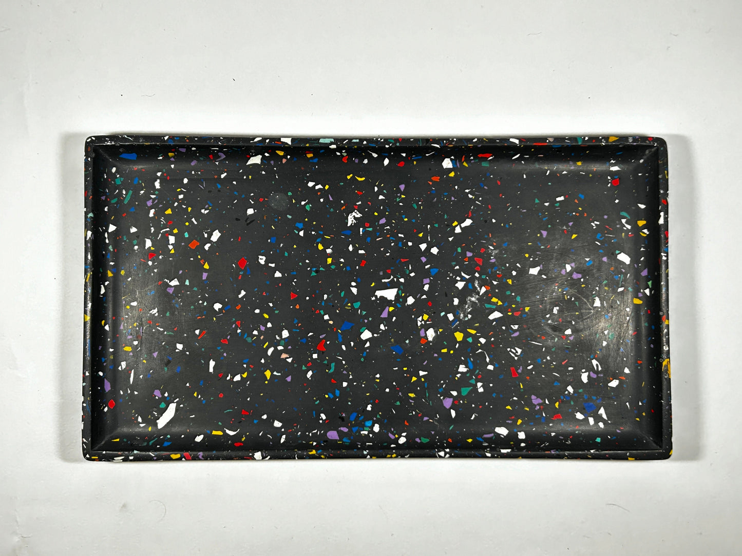 Black tray with colourful speckles on a white background