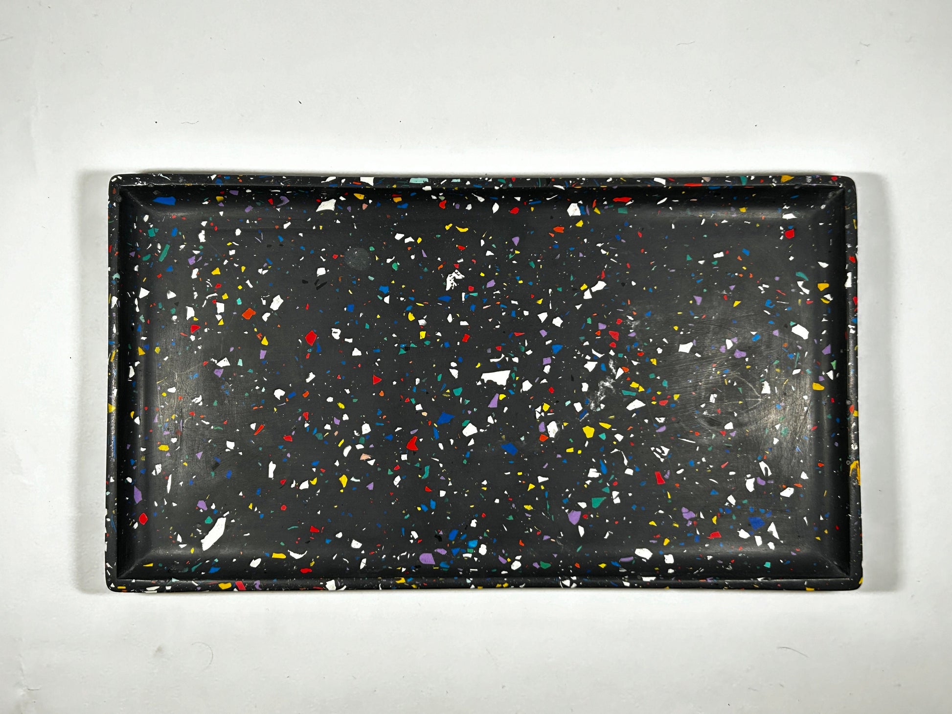 Black tray with colourful speckles on a white background