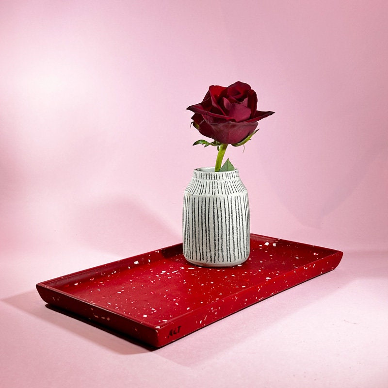 Red terrazzo tray and a vase with a rose on a pink background