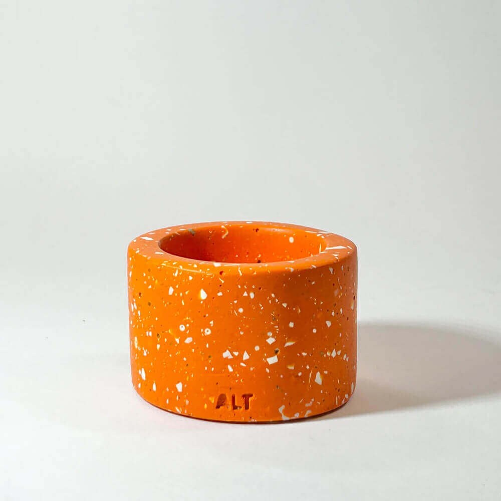 Orange terrazzo-patterned tea light holder on a light grey background