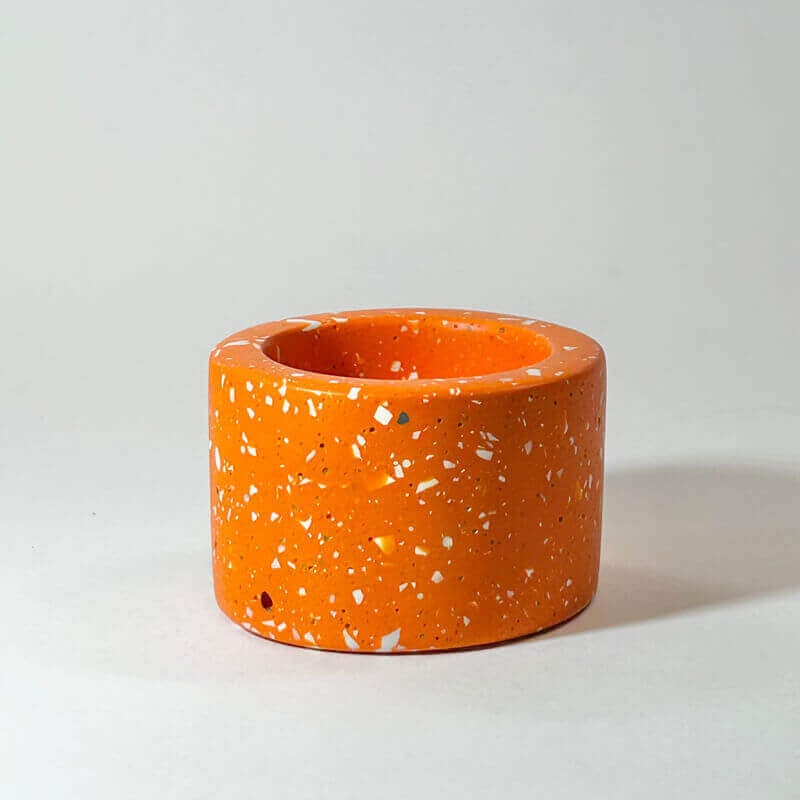 Orange terrazzo-patterned tea light holder on a light grey background