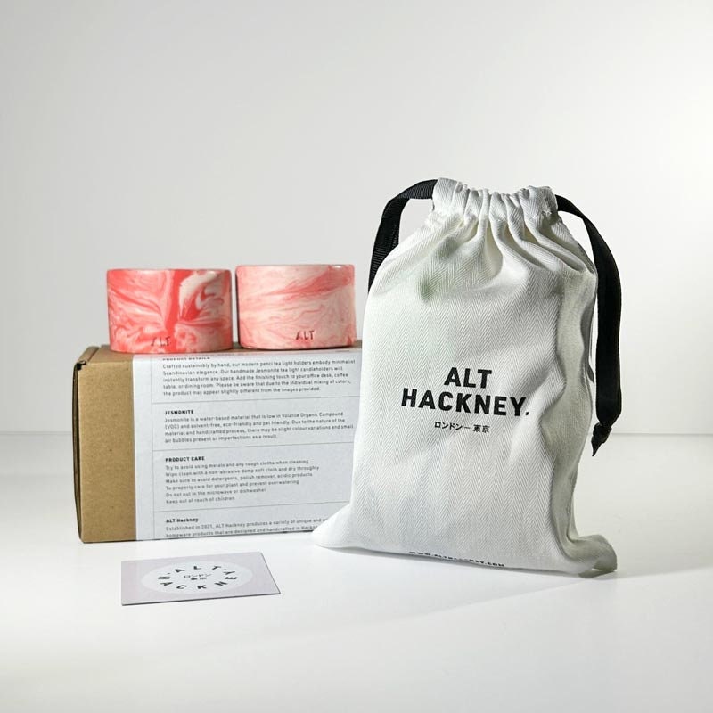 White drawstring bag with 'ALT HACKNEY' branding, pink tea light holders, and a cardboard box on a white background.