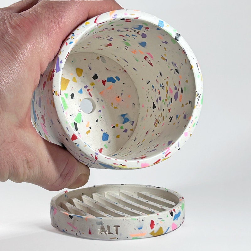 Colourful textured Plant pot with a hand holding it on a white background