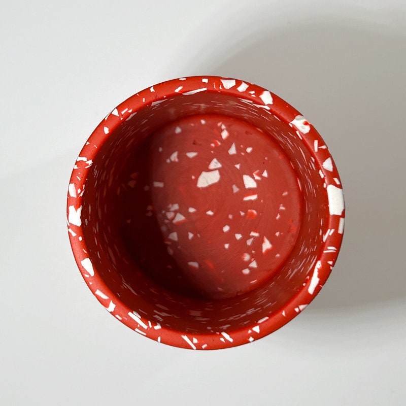 Red ceramic bowl with white speckles on a light gray background
