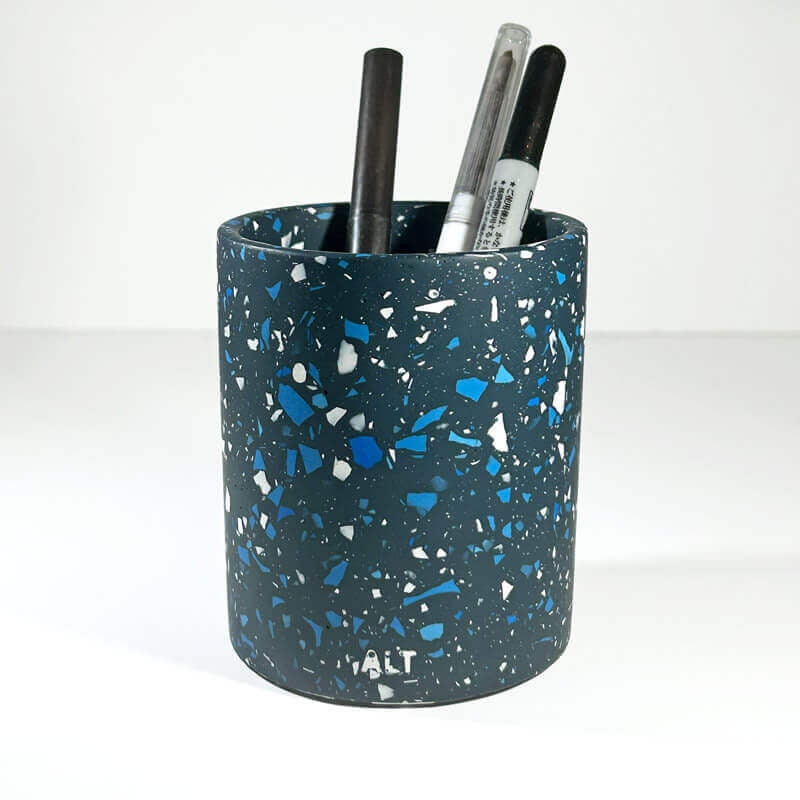 Blue speckled pen holder with pens on a white background