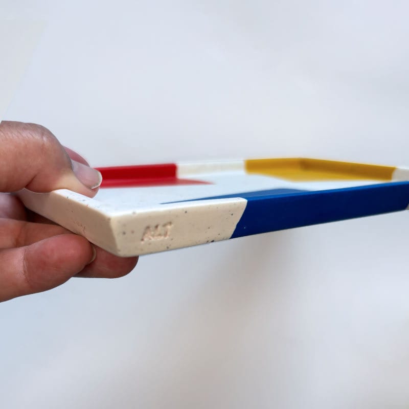 Hand holding a colourful chunky terrazzo tray with a white background