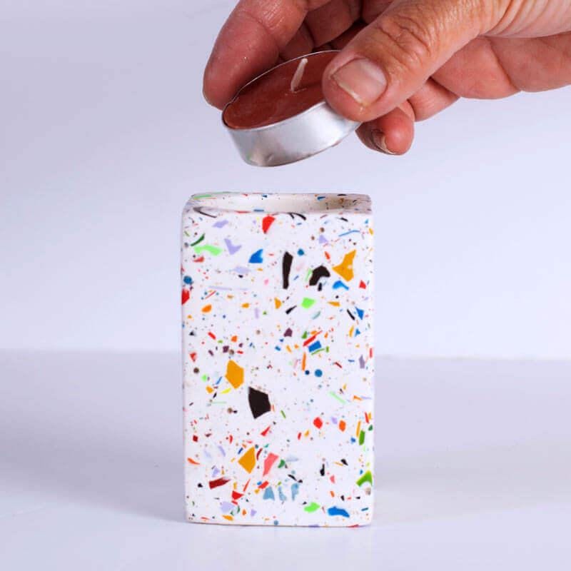 Rainbow confetti rectangular tea light candle holder with a hand holding a tea light candle on a white background